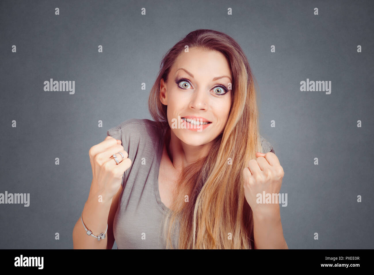 Femme stupéfaite poings serrés les mains de pompage dans l'attente sur le point de gagner une loterie ou quelque chose d'isolé sur fond gris mur studio avec copie espace. Banque D'Images