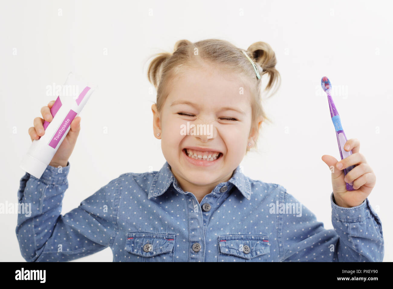 Soins dentaires pour enfants concept. Jolie fillette de cinq ans, tenant sa brosse à dents et du dentifrice et montrant ses dents dans le grand sourire. Banque D'Images