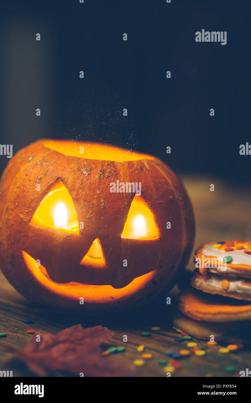 Arrière-plan de l'Halloween à la citrouille sur la table en bois. Sourire tête de citrouille avec des bougies, feuilles d'automne et d'Halloween cookies. Close up Banque D'Images
