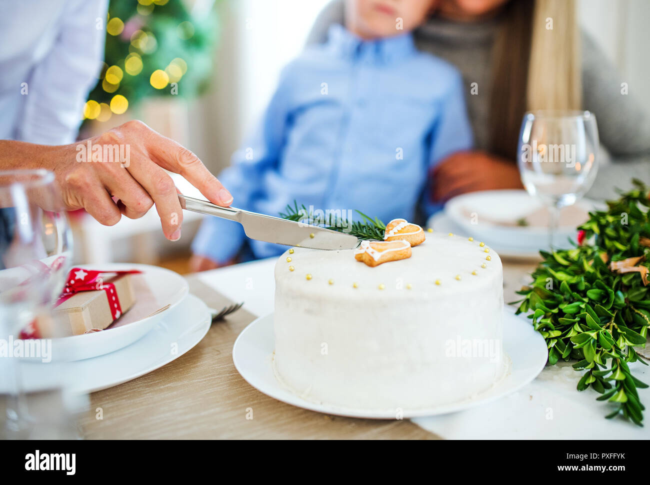 Femme méconnaissable avec la famille de couper un gâteau de Noël. Banque D'Images