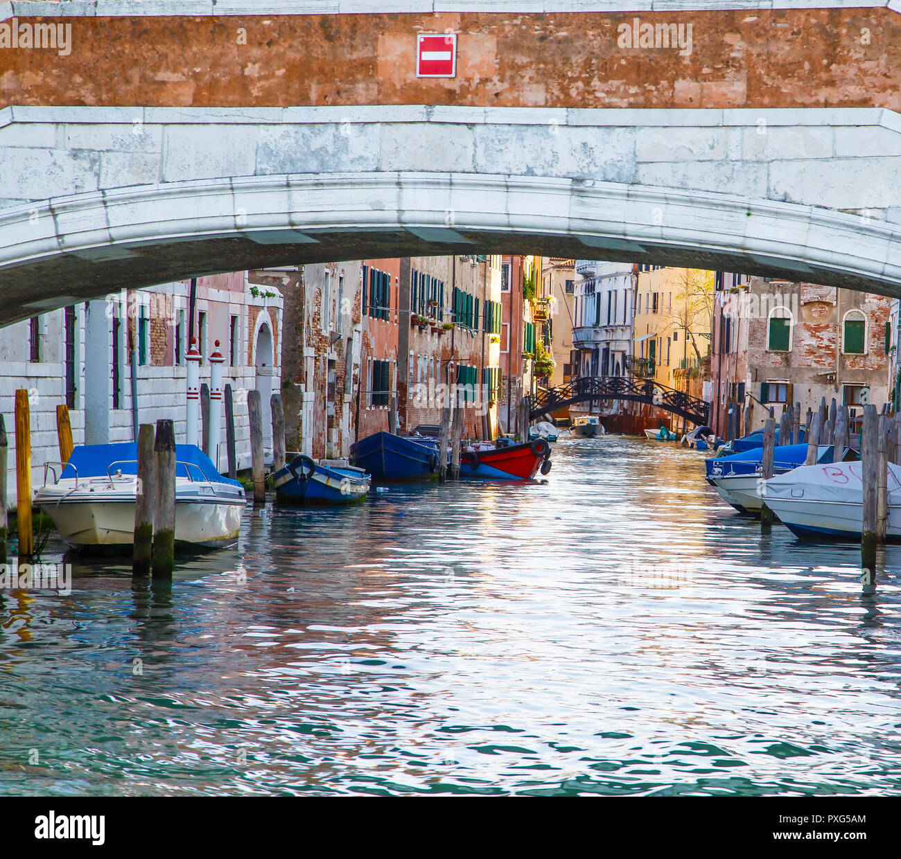 La lumière de l'après-midi le long d'un canal bordé de maisons aux volets colorés et bateaux à Venise, Italie Banque D'Images