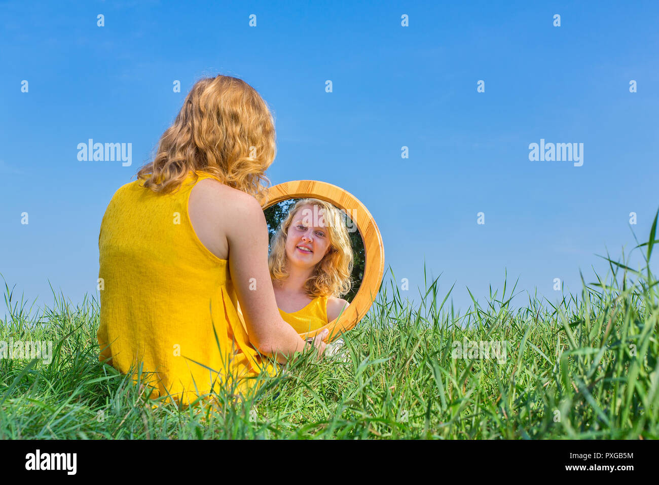 Red-haired woman se trouve à l'extérieur de l'image à son miroir Banque D'Images