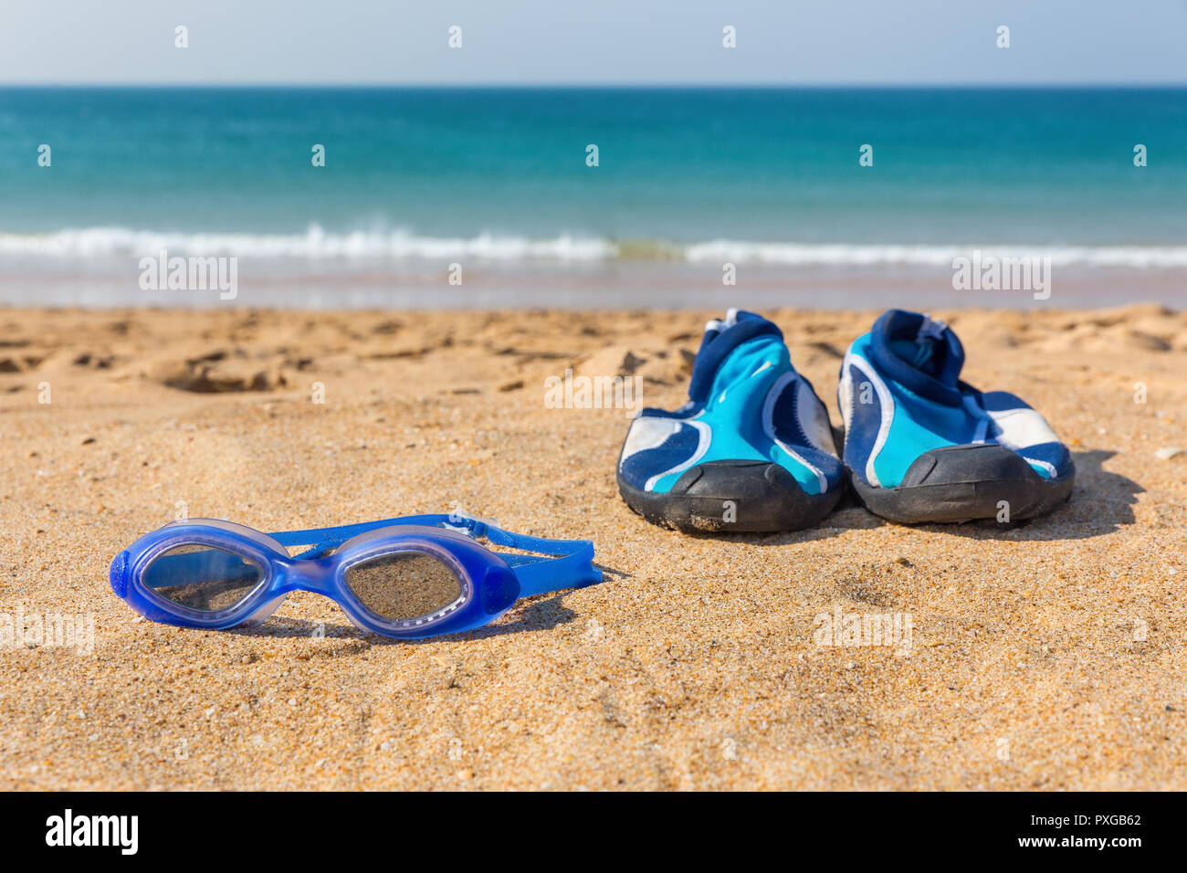 Lunettes de natation bleu et souliers d'eau se trouvant à l'autre avec vue sur la mer Banque D'Images