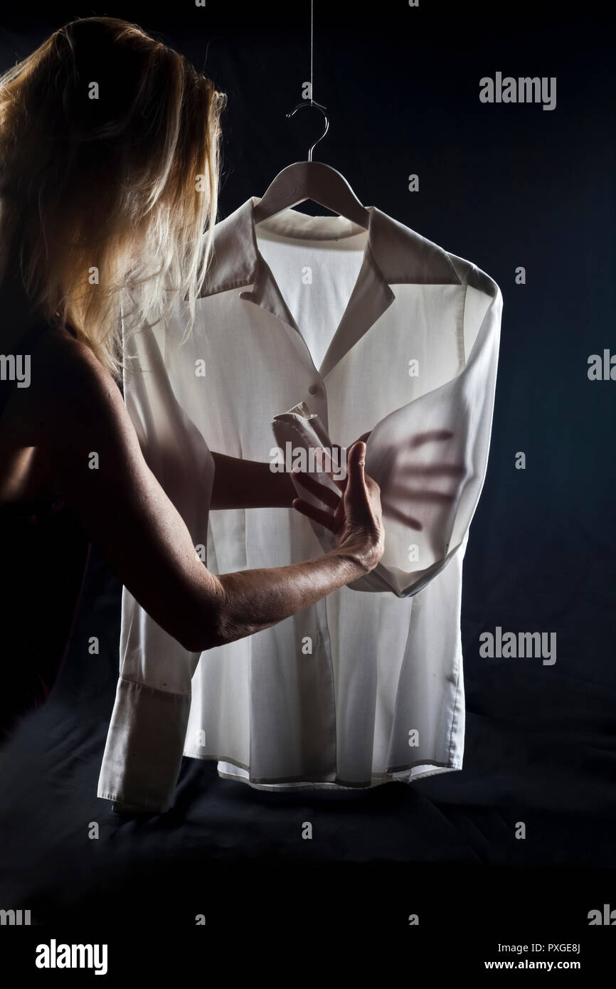 Sombre et moody photographie d'une femme inspecte un chemisier Banque D'Images