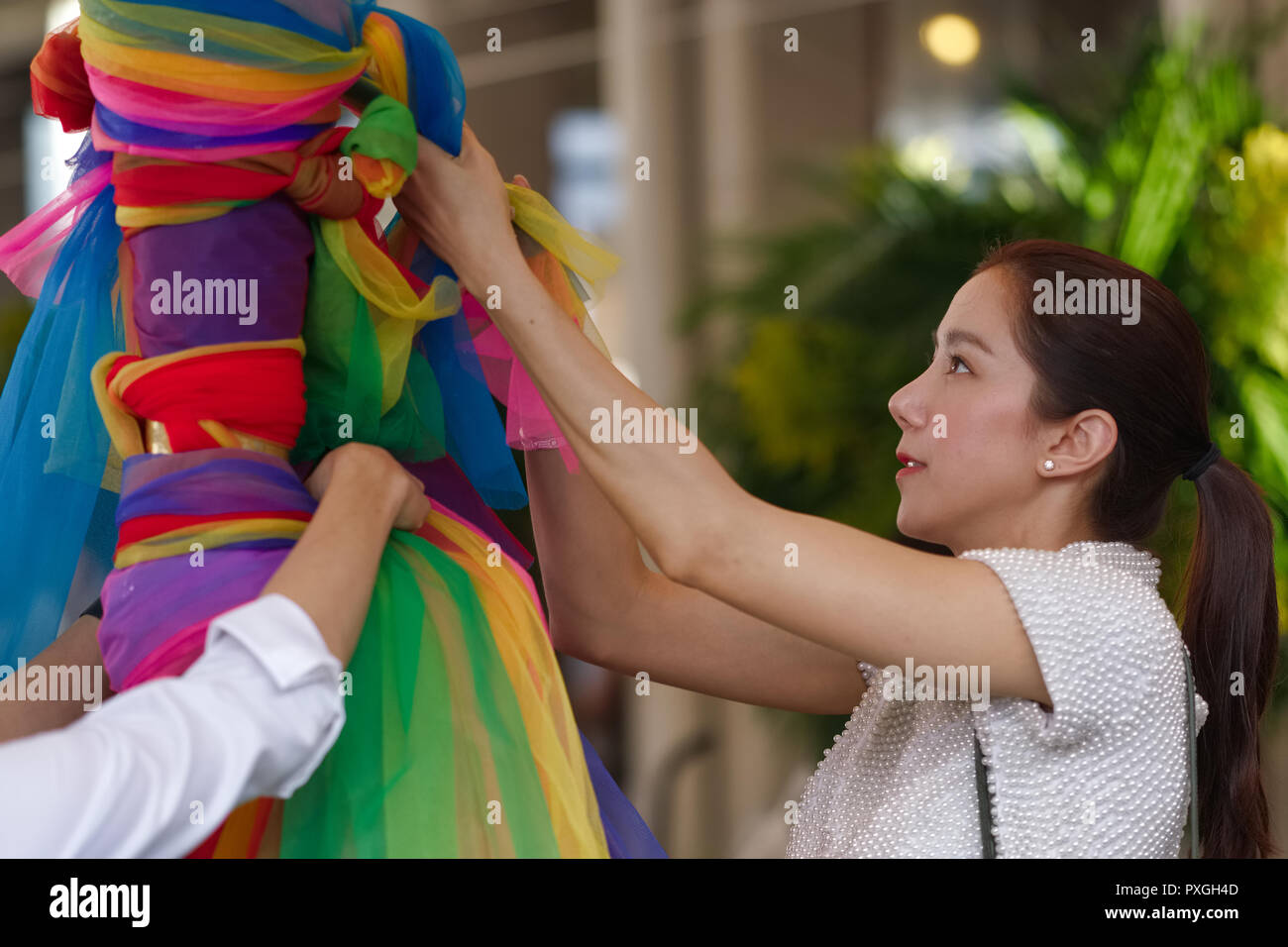 Un plat thaïlandais actrice au pilier de la ville de culte (Lak Mueang / Muang), Bangkok, Thaïlande, ornant l'un des piliers sur le site avec des bandes de tissu coloré Banque D'Images