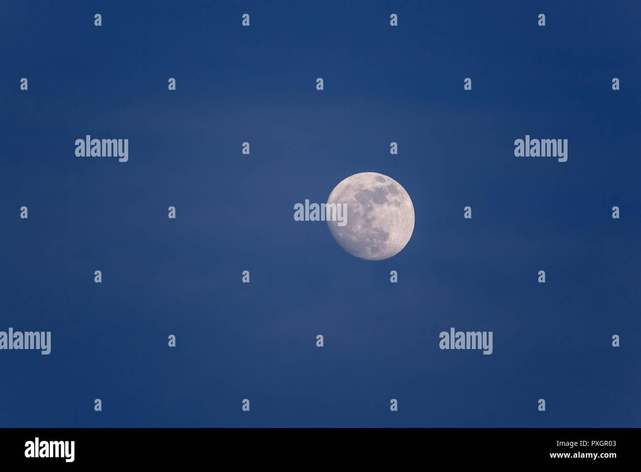 Pleine lune dans journée à heure bleue avec des nuages blancs Banque D'Images