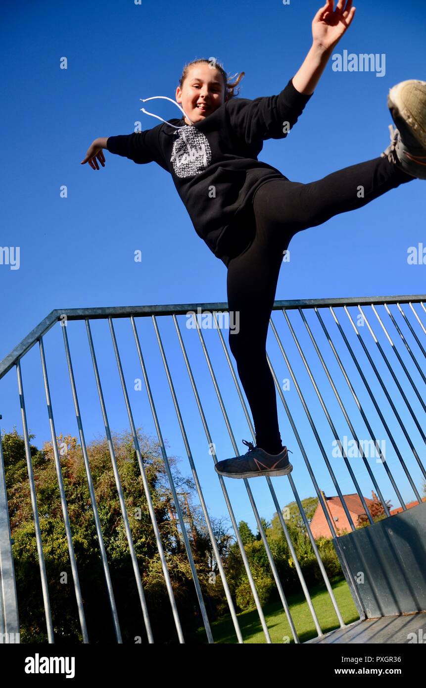 Jeune fille dans le noir top et leggings sauter de joie, le Deep blue sky background, en Angleterre. Banque D'Images