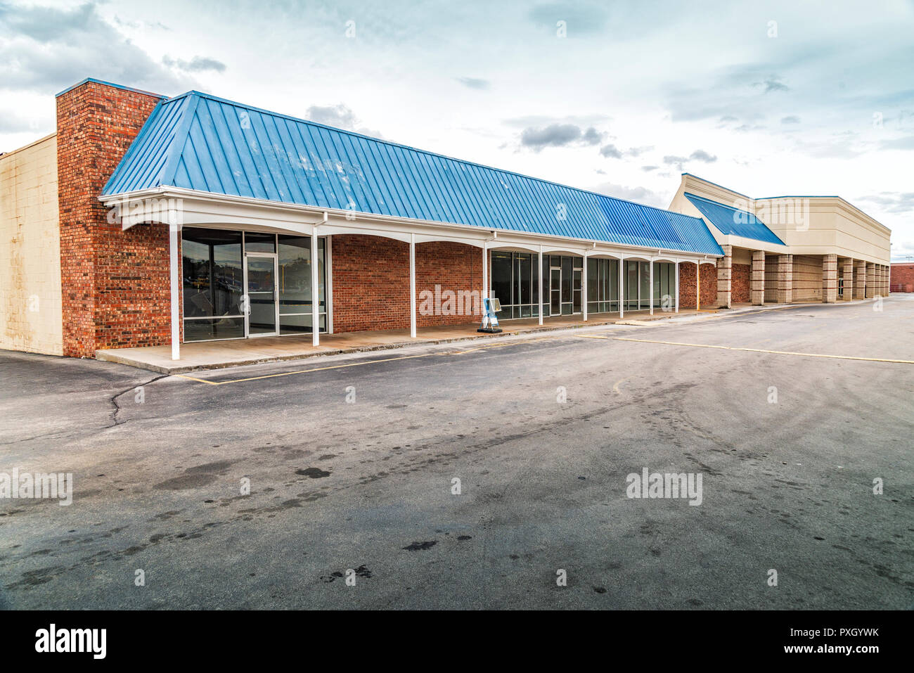Capture d'une ancienne horizontale rict vacant centre commercial avec un parking vide et ciel nuageux. Banque D'Images