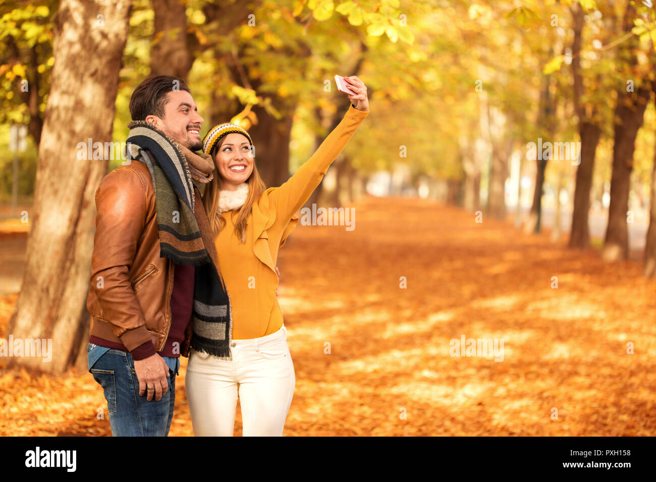 Prendre un beau couple avec selfies un téléphone d'un parc à l'automne Banque D'Images