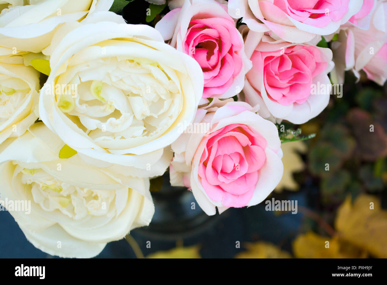 Bouquet de fleurs rose blanche et rose en vase en pierre noire sur fond de  carreaux en pierre noire et de l'automne les feuilles tombées sur le sol.  Photo en gros plan