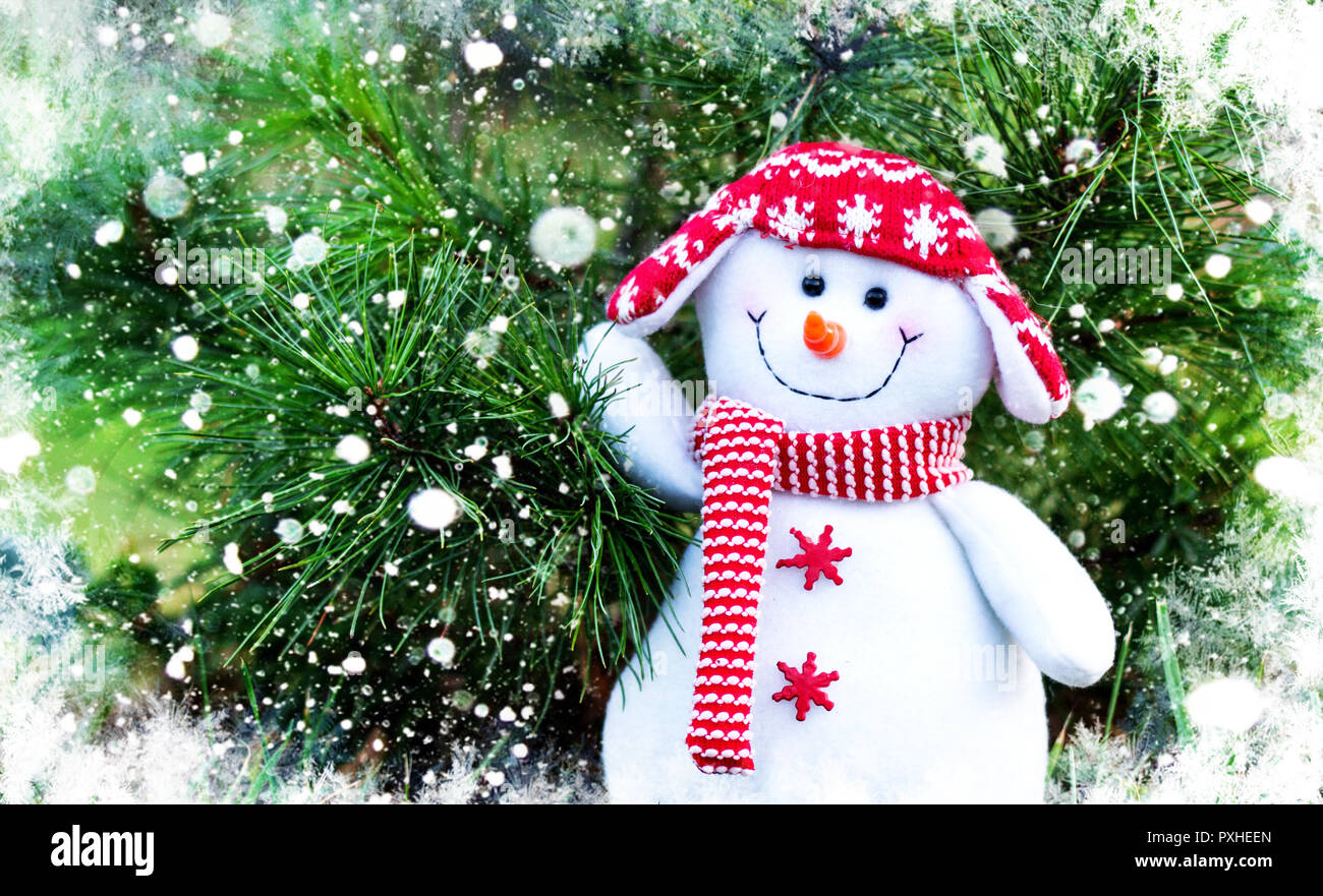 Bonhomme de neige dans un chapeau et un foulard rouge sur un fond d'arbres de Noël Banque D'Images