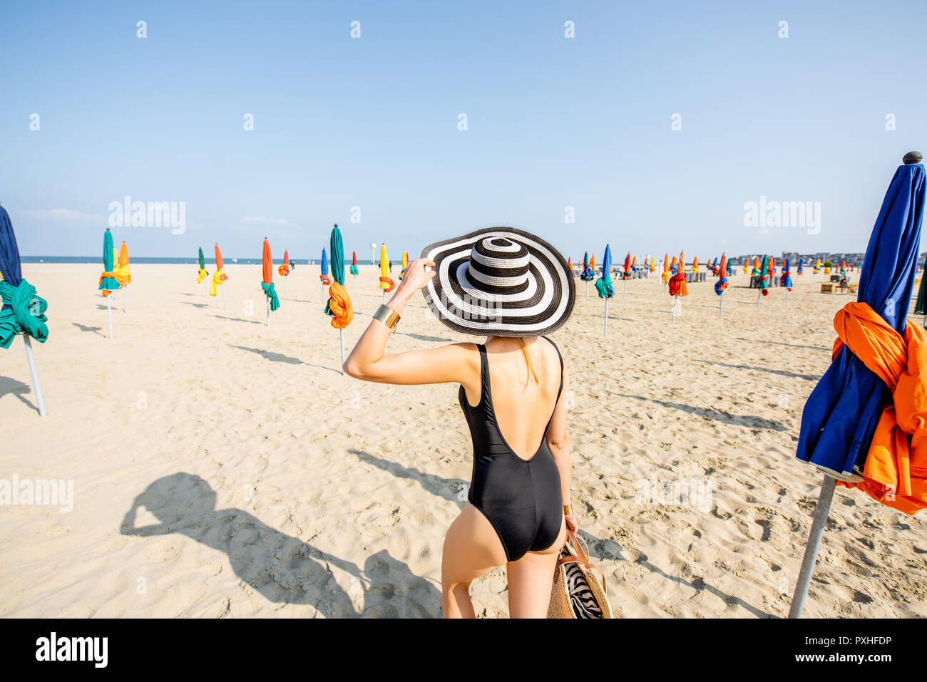 Femme Marche Sur La Plage Avec Parasols Colorés à Deauville