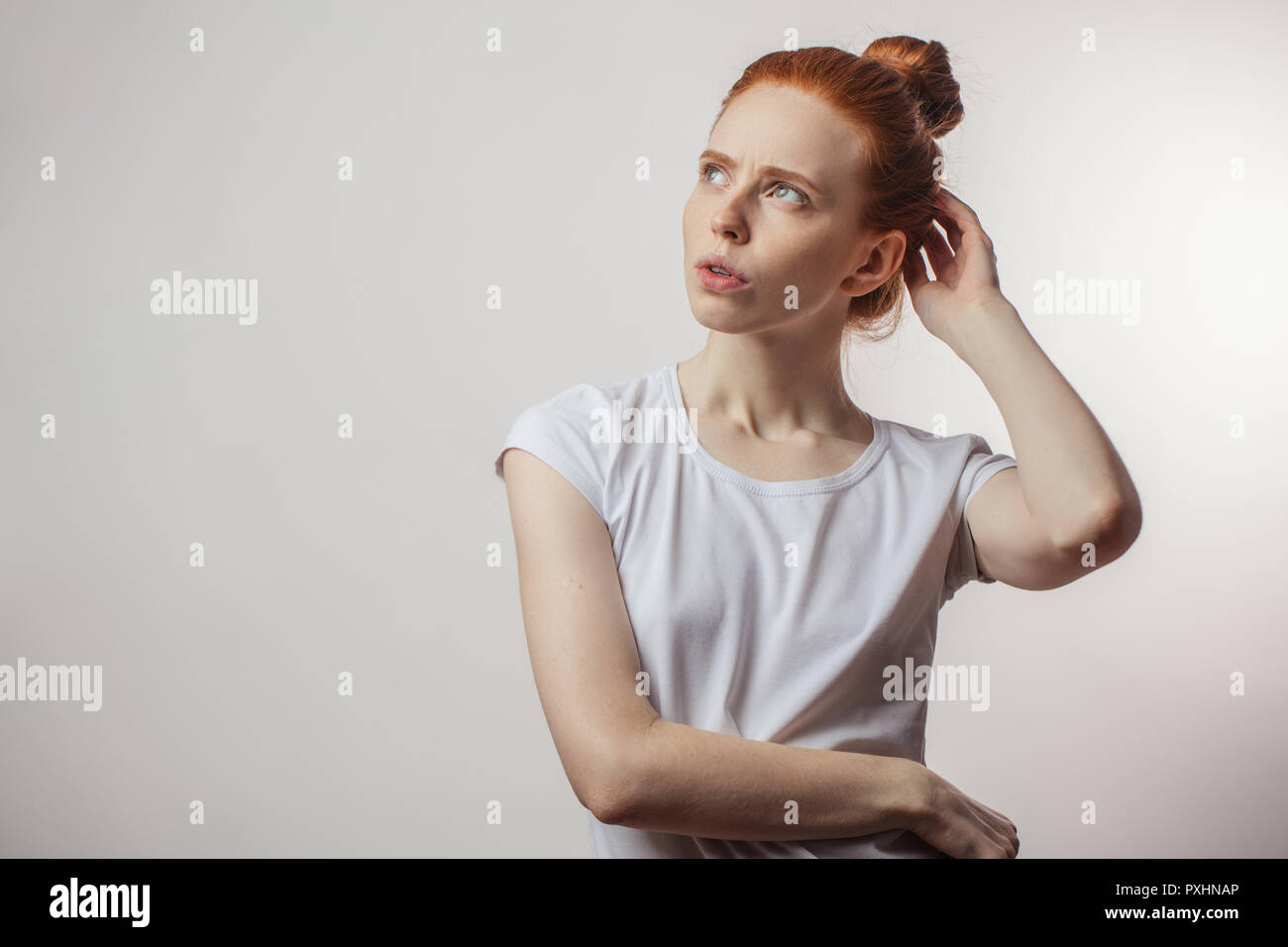 Redhaired woman with pensive expression isolé sur fond blanc. Banque D'Images
