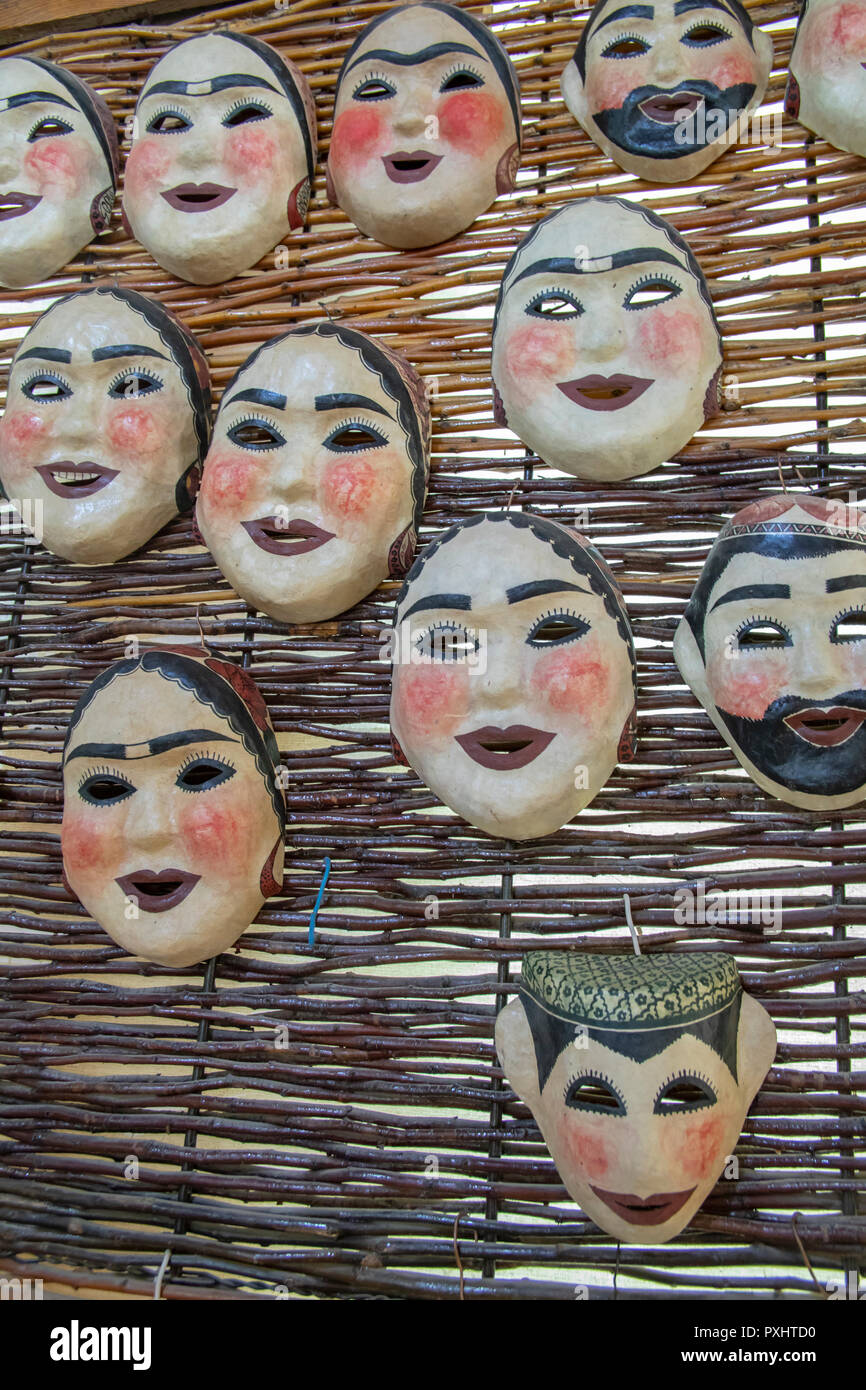Les masques en papier mâché d'hommes et de femmes visages dans des foulards et des chapeaux traditionnels sur l'affichage à Samarkand, Ouzbékistan. Banque D'Images