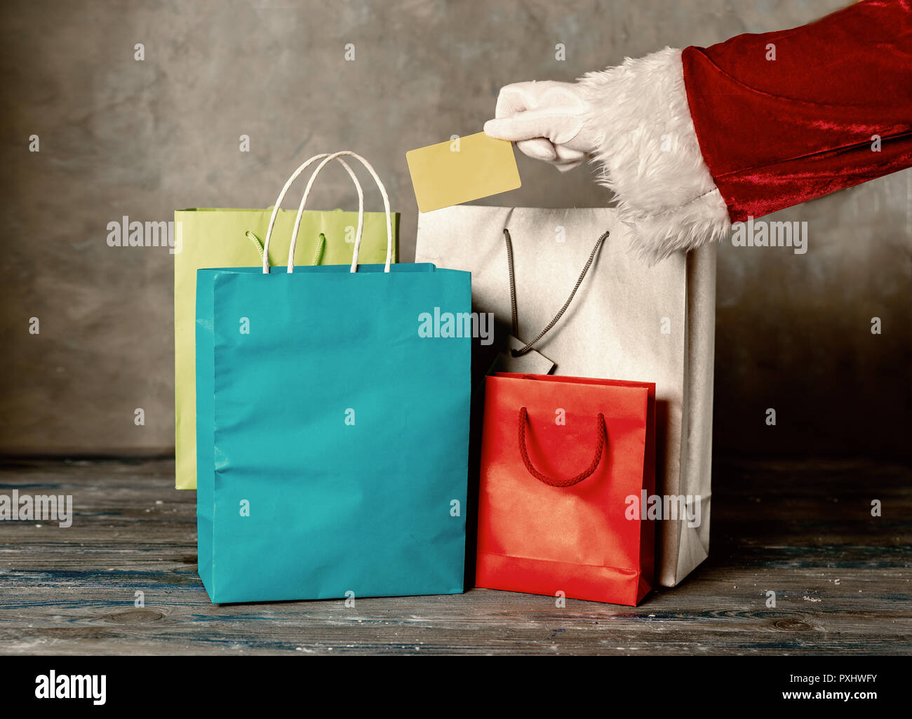 Santas main tenant une carte en plastique contre l'arrière-plan gris Banque D'Images