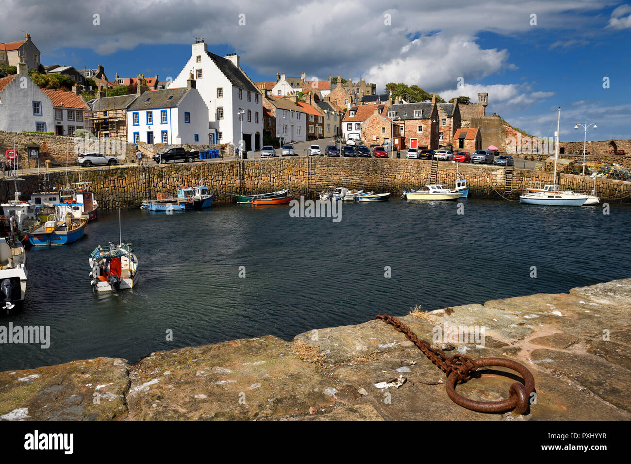 Bateau de pêcheur en revenant à Crail Harbour avec piles en pierre et en fer l'anneau d'amarrage sur la mer du Nord l'Ecosse UK Banque D'Images