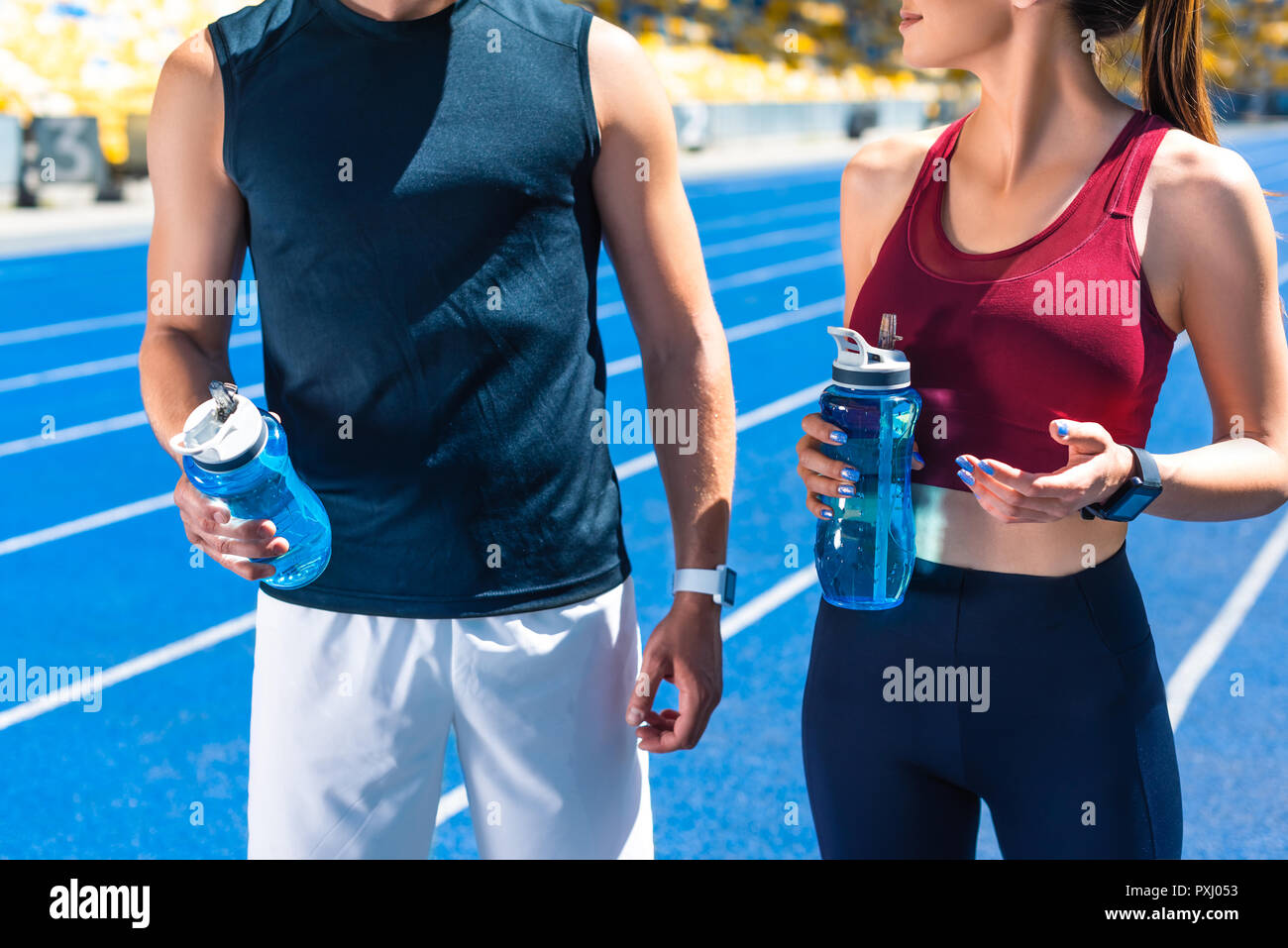 Cropped shot de monter avec deux bouteilles d'eau sur une piste de course au stade de sport Banque D'Images