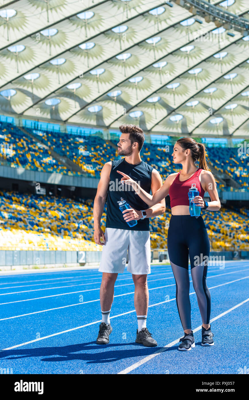 Jeune couple fit avec bouteilles d'eau sur une piste de course au stade de sport Banque D'Images
