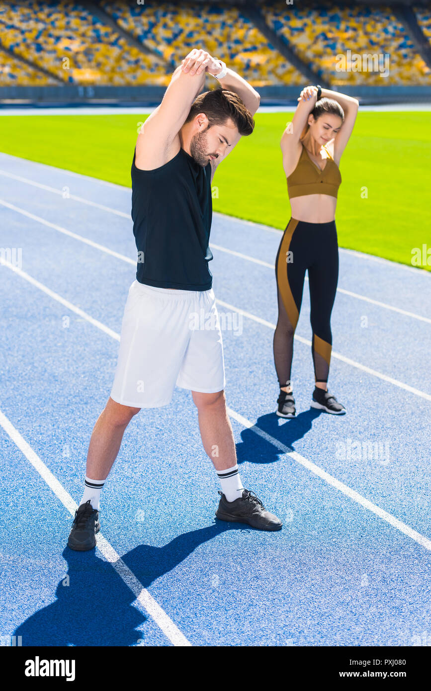 Jeune couple d'athlètes l'échauffement avant l'entraînement sur une piste de course au stade de sport Banque D'Images