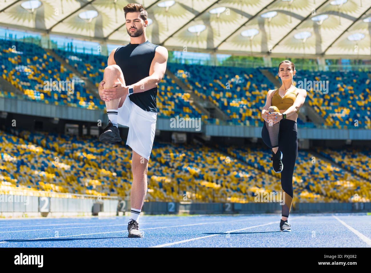 Jeune couple sportif réchauffe les jambes avant la course sur une piste de course au stade de sport Banque D'Images