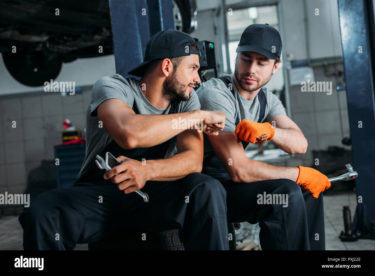 Les travailleurs manuels tapotant poings ensemble dans mechanic shop Banque D'Images