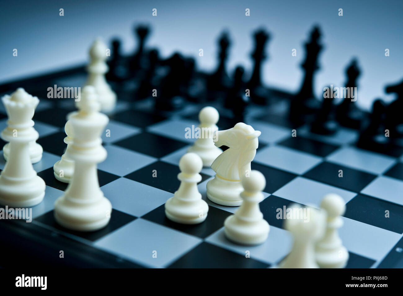 Grossissement des pièces d'échecs noires sur un échiquier noir et blanc avec mise au point sélective et profondeur de champ peu importante. Banque D'Images