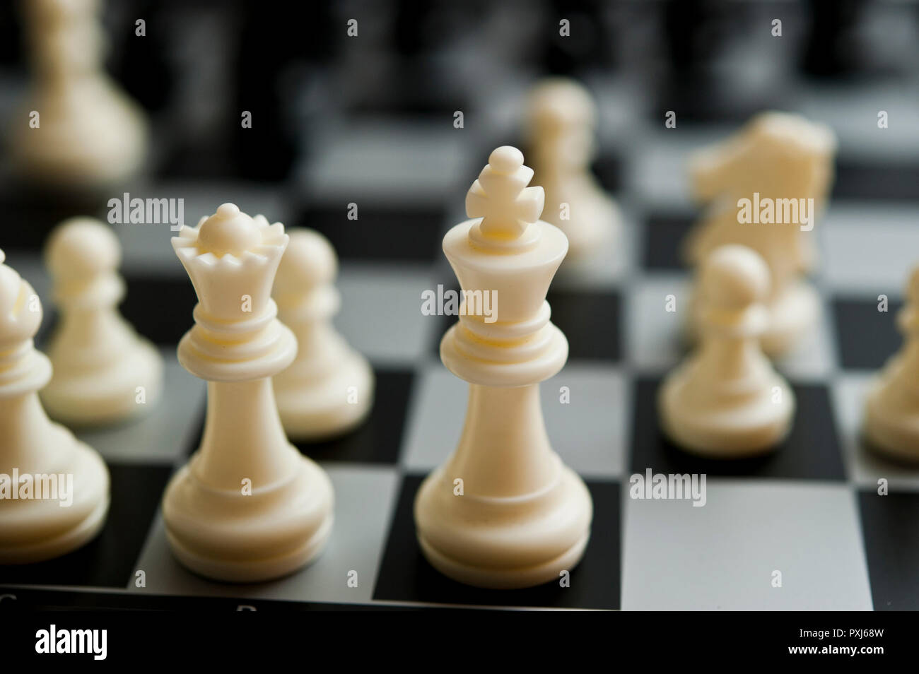Grossissement des pièces d'échecs noires sur un échiquier noir et blanc avec mise au point sélective et profondeur de champ peu importante. Banque D'Images
