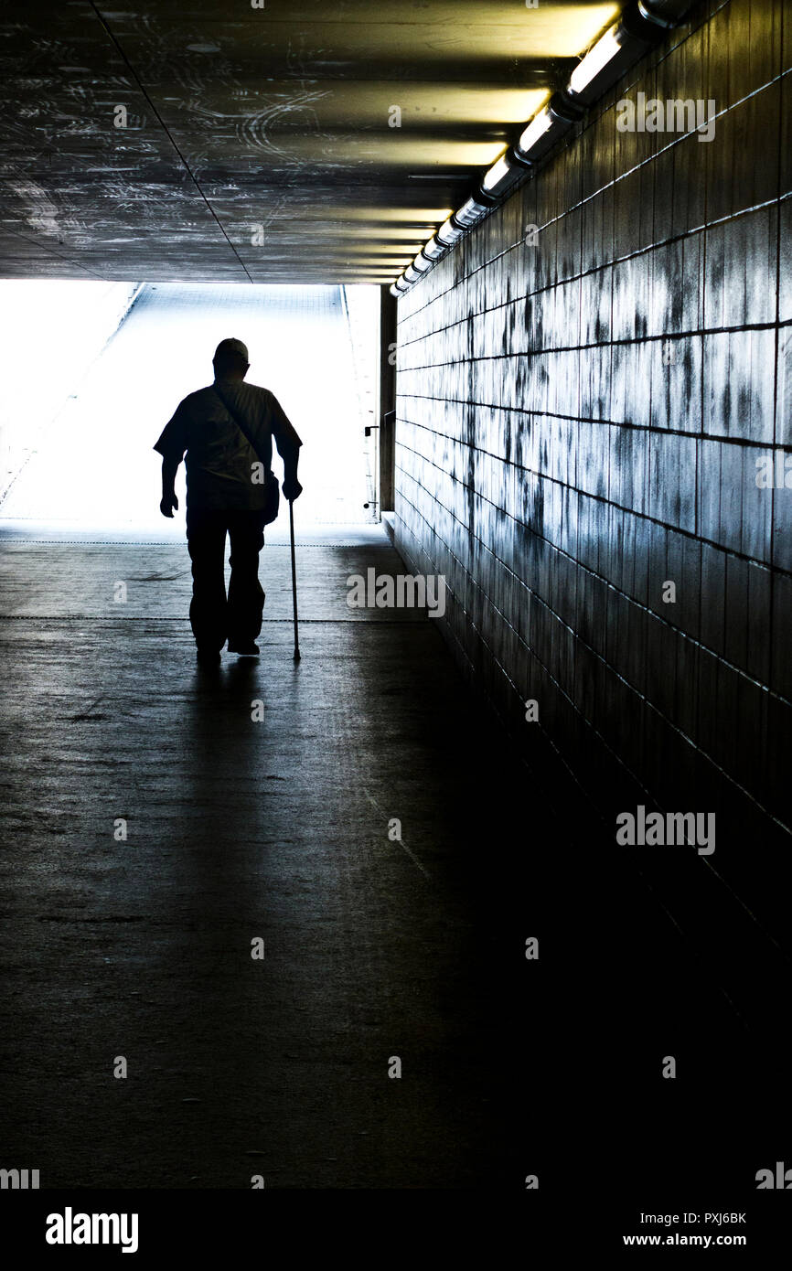 Silhouette d'un homme marchant avec un bâton dans un passage inférieur Banque D'Images