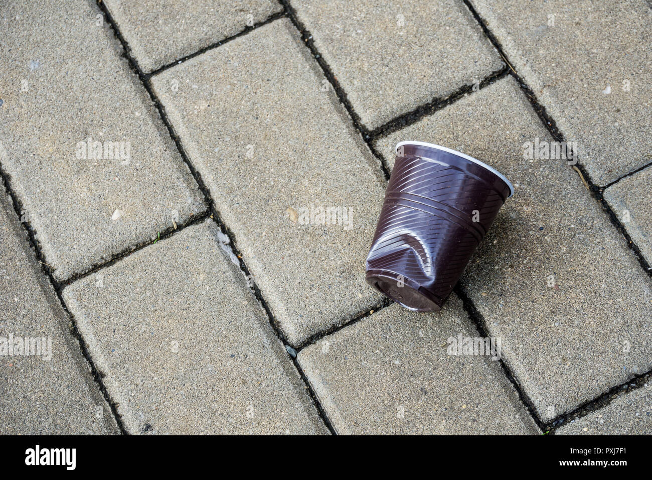 Tasse en plastique broyé et écrasé sur la pierre sur rue dans city show de déchets pollution atmosphérique, avec des paquets d'aliments de préparation rapide Banque D'Images