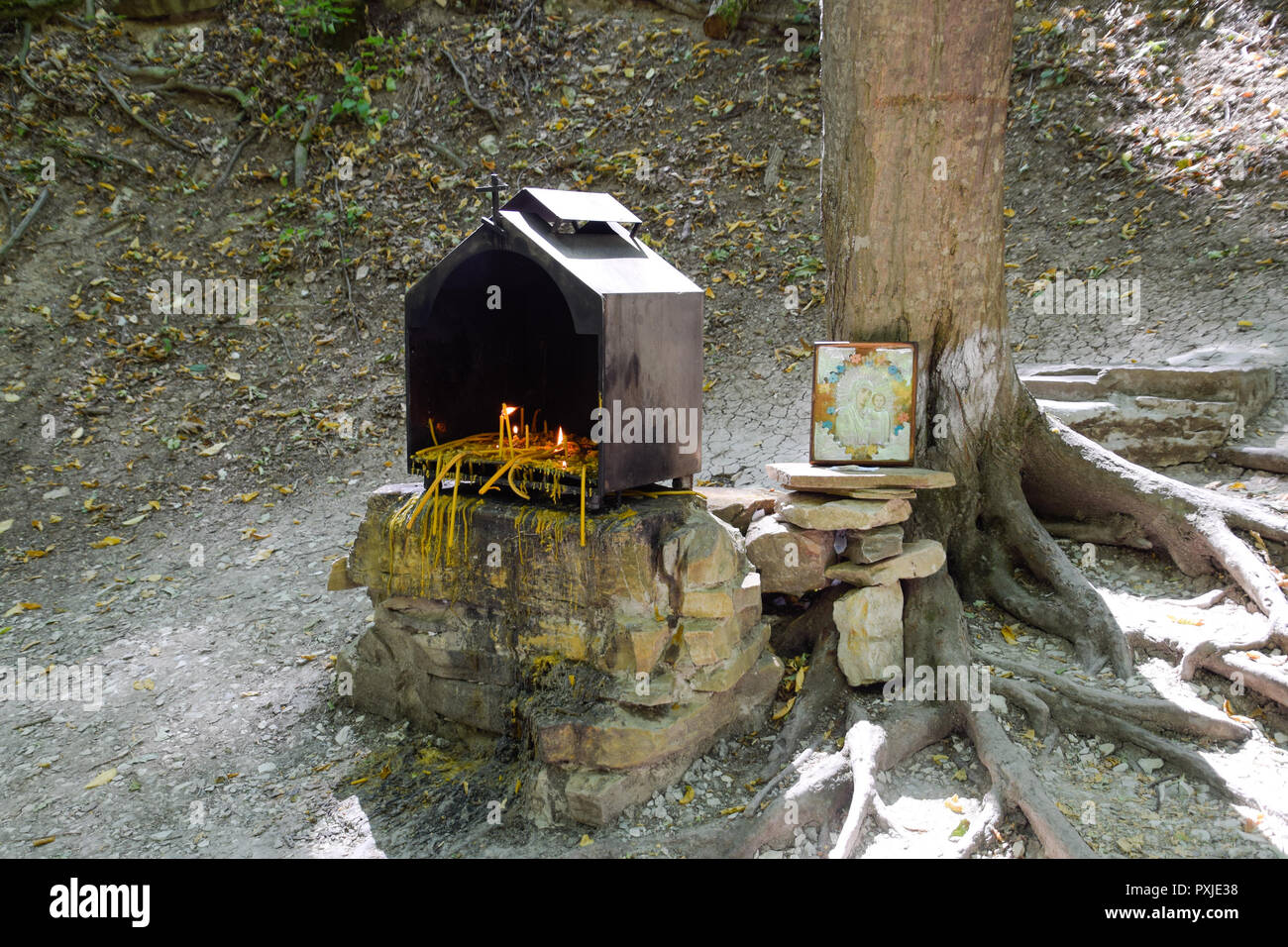 Bougies orthodoxe dans la forêt sous un arbre dans une boîte. La prière pierre par la route Banque D'Images