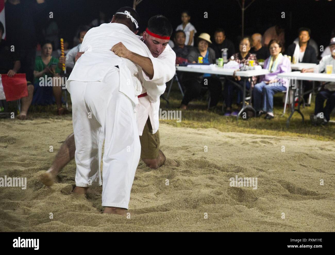 Lance le Cpl. Giovanni L. Ramires (centre-droit) leg balaie son adversaire,  10 juin 2017, au cours de l'Assemblée Henoko Okinawa-Style Mae-No au  tournoi de Sumo-Hama Champ dans Henoko, Okinawa, Japon. Lors d'un