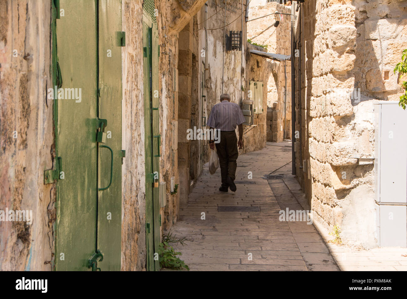 Vieil homme vu de dos, la marche à travers les rues de la vieille ville historique d'Akko, Israël. Banque D'Images