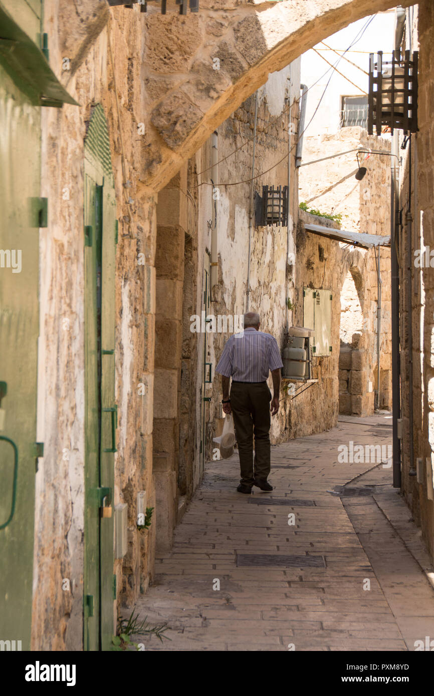 Vieil homme vu de dos, la marche à travers les rues de la vieille ville historique d'Akko, Israël. Banque D'Images