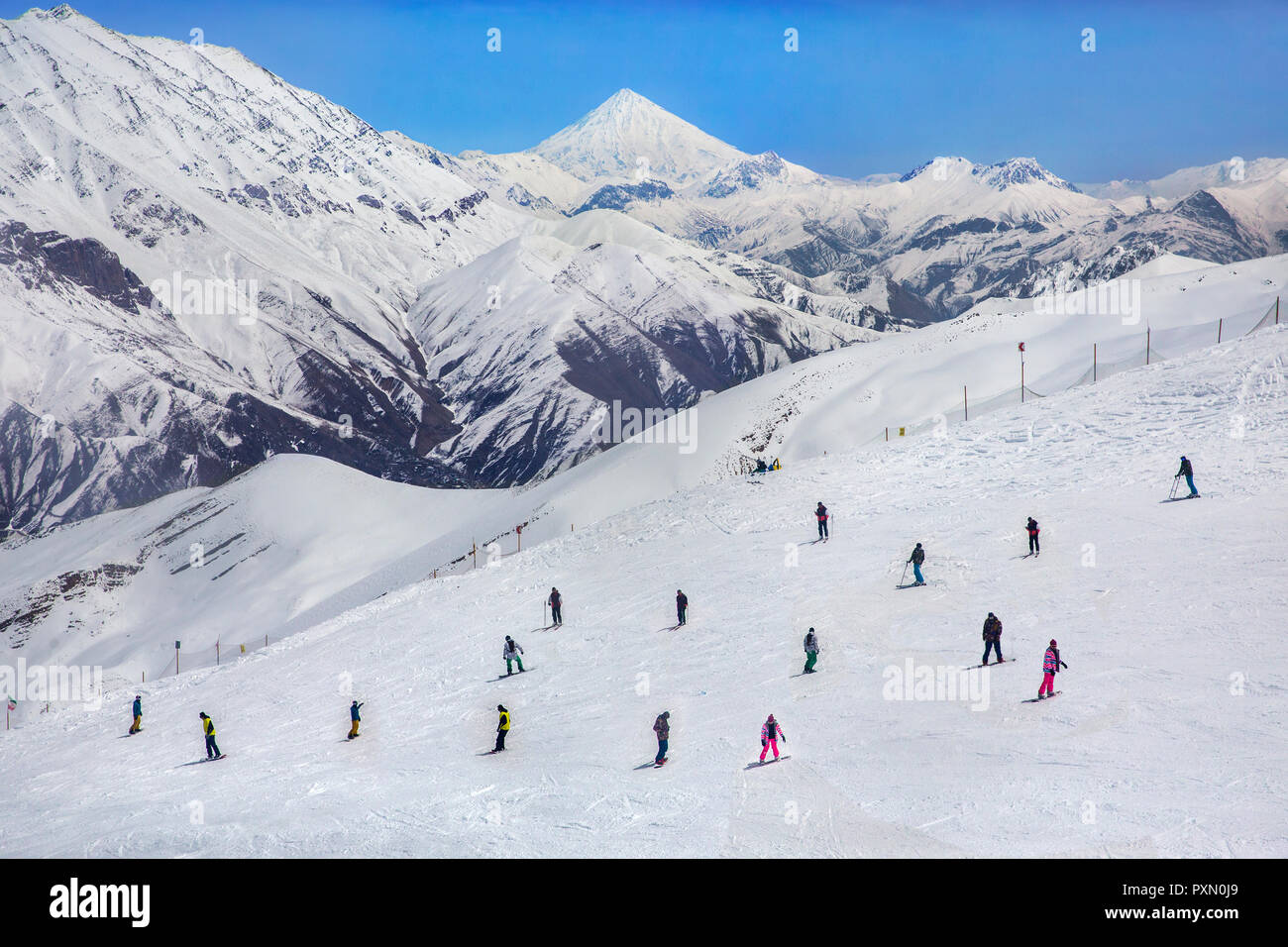 Vue sur les skieurs et le Mont Damavand depuis la station de ski de Dizin à Téhéran, Iran. Banque D'Images