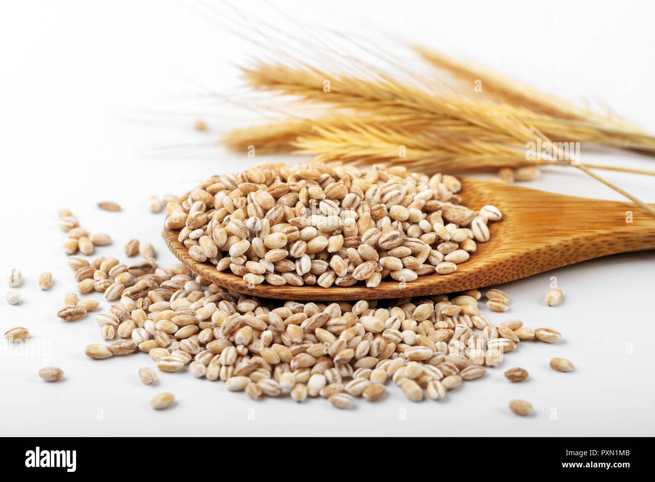 Dans l'orge perlé cuillère en bois sur fond blanc Banque D'Images