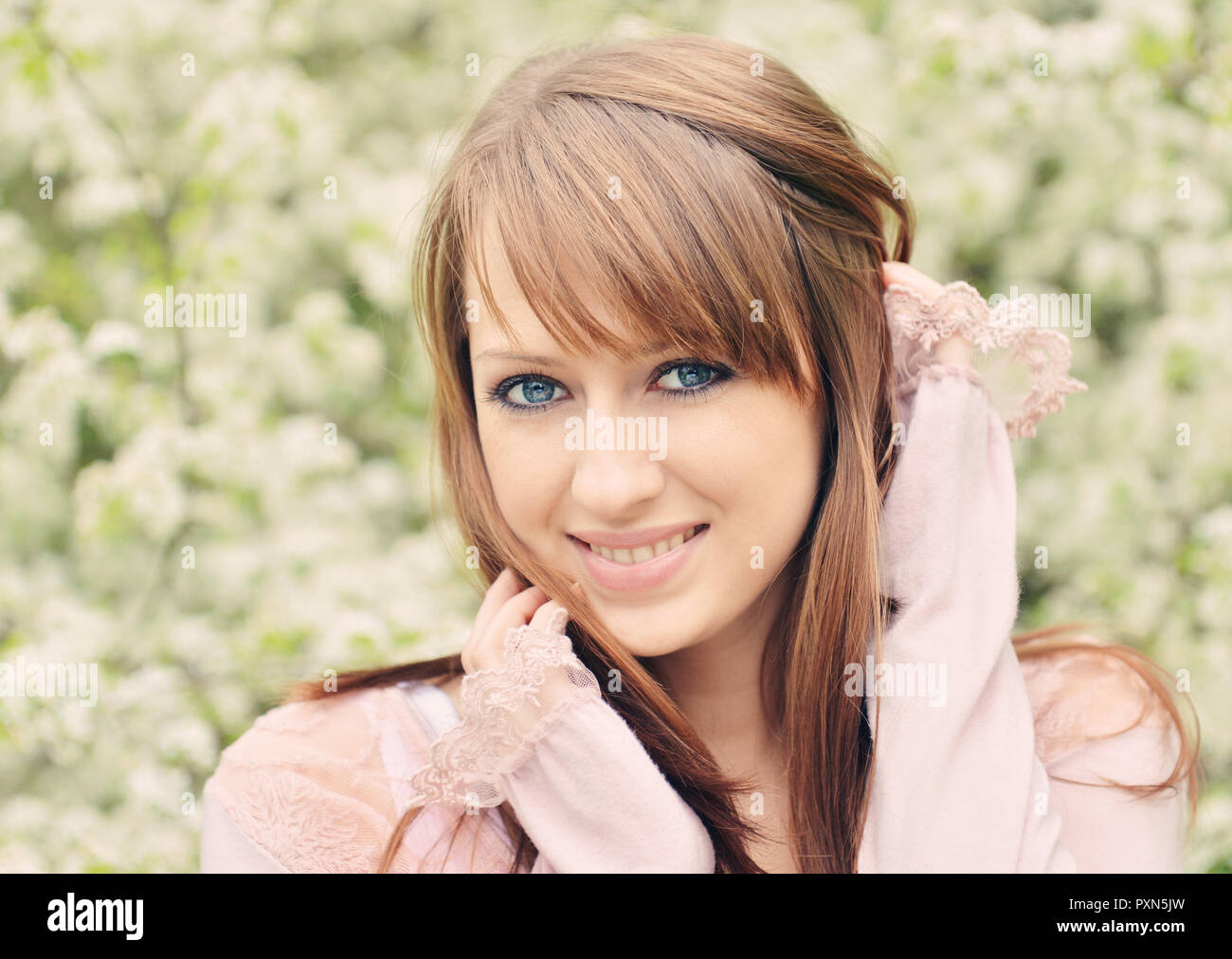 Belle jeune fille sur fond de fleurs de printemps Banque D'Images