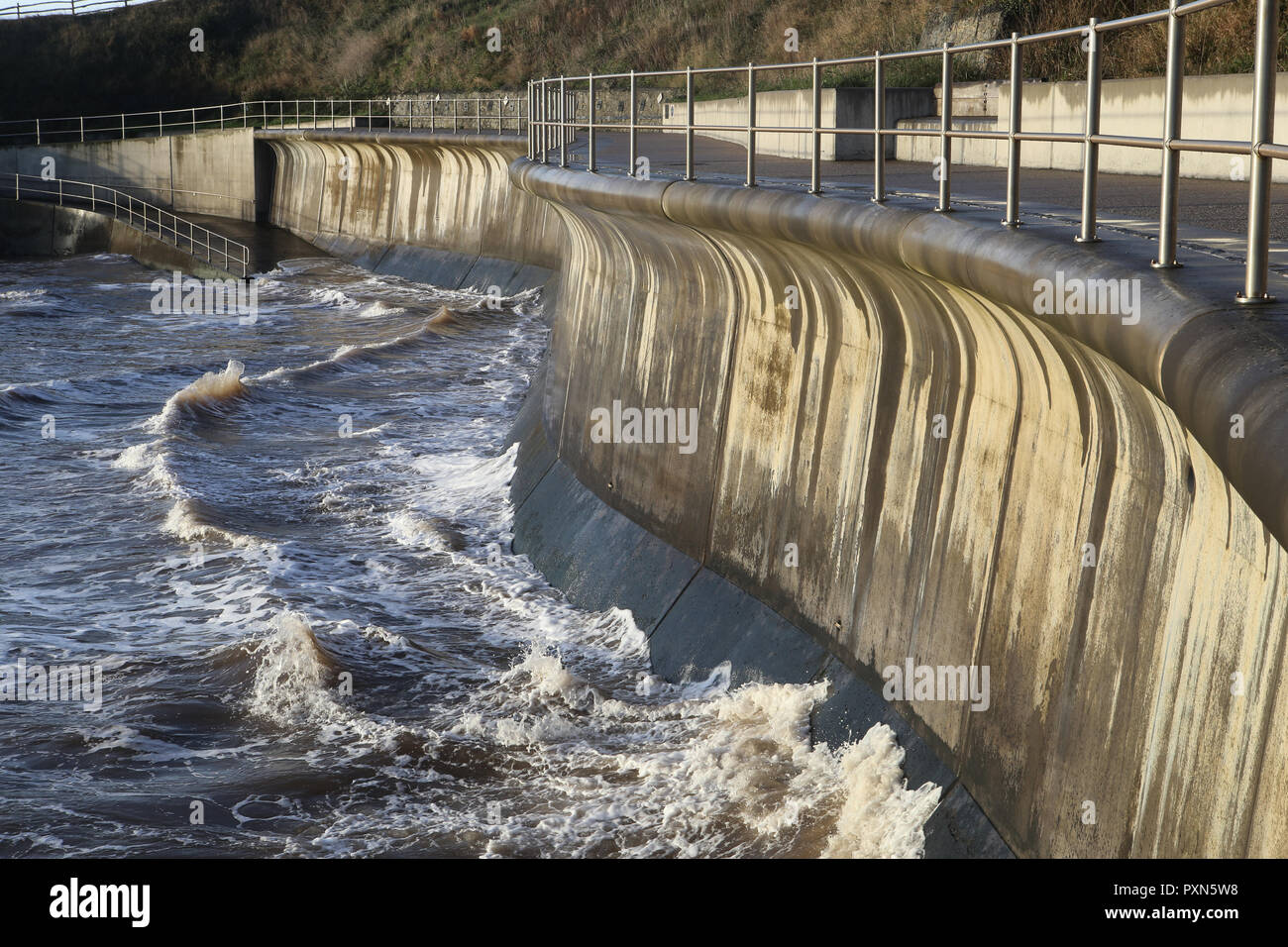 Les vagues agitées contre un mur de défense contre la mer de béton Banque D'Images