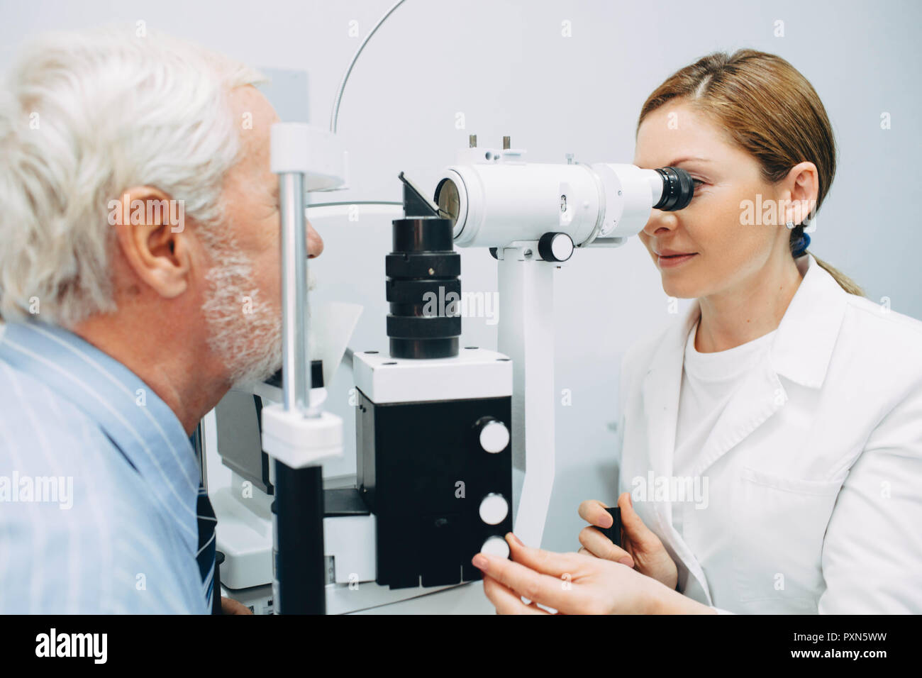Docteur optométriste examinant les yeux du vieil homme avec un équipement oculaire spécial Banque D'Images