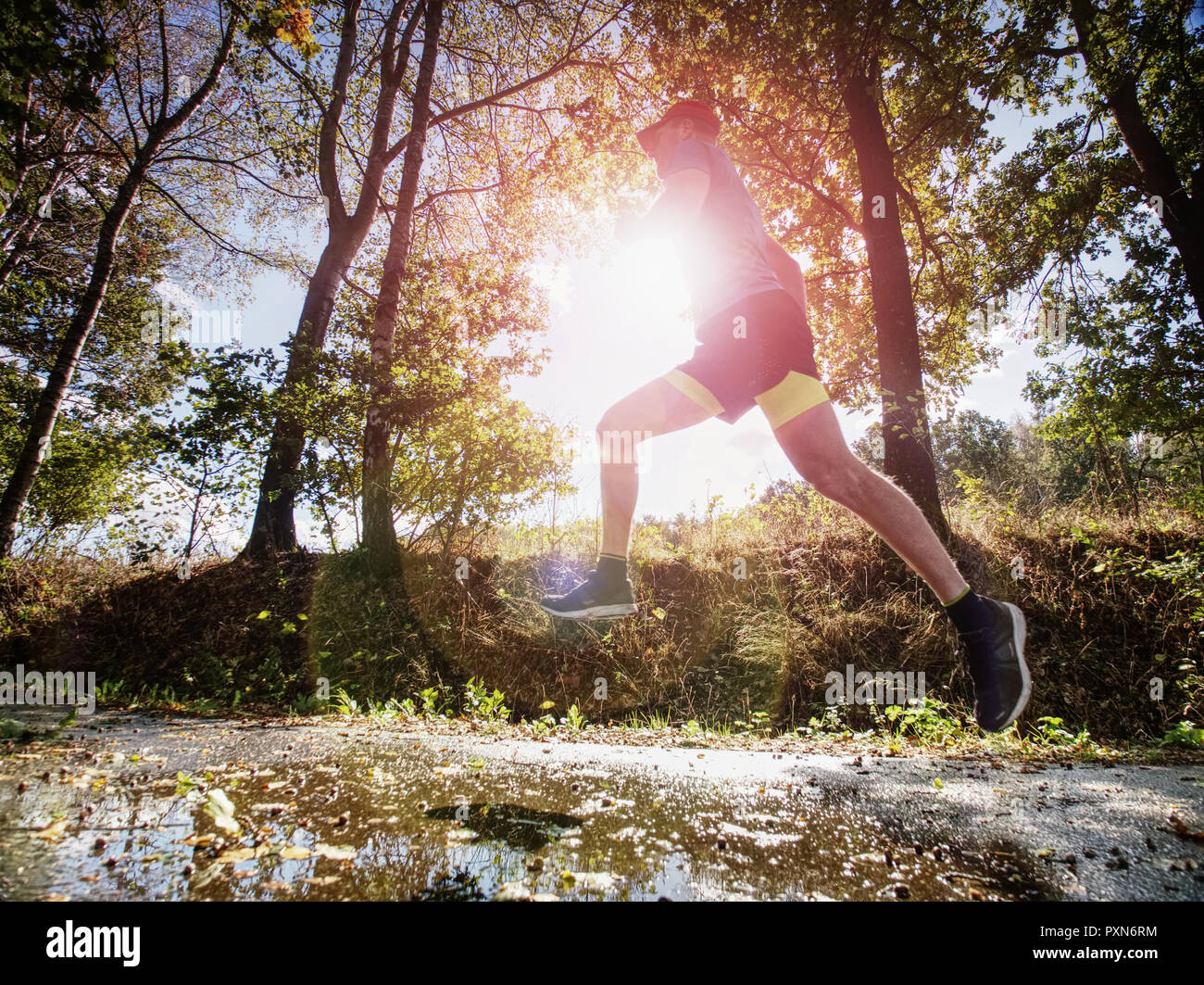 Haut de jogging homme sport dans les arbres d ombre avec la lumiere du soleil derriere lui tout en portant un short noir jaune et bleu tenue de jogging Photo Stock Alamy