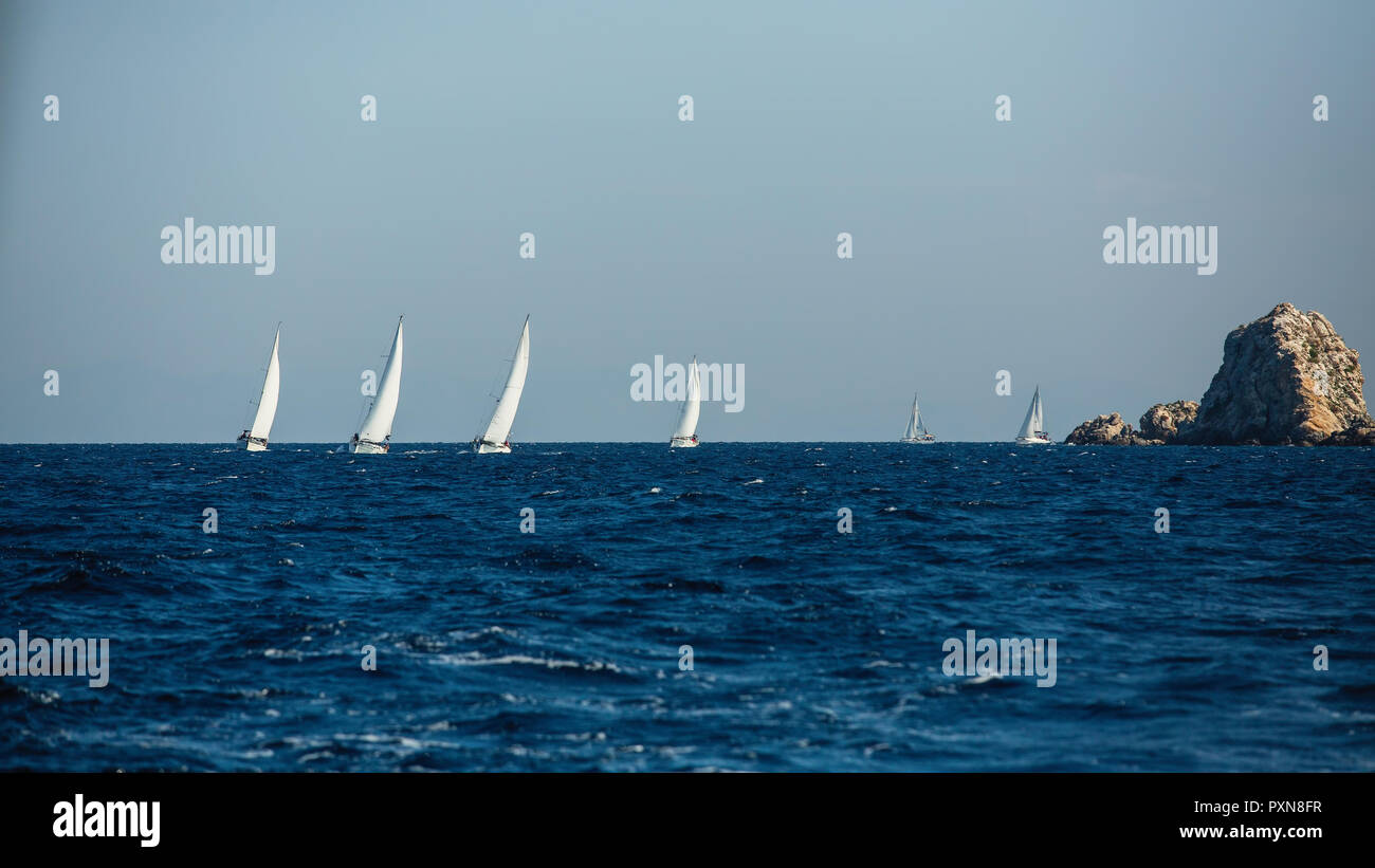 Yacht Bateaux groupe avec voiles blanches près des rochers dans la mer Egée. Régate de voile. Banque D'Images