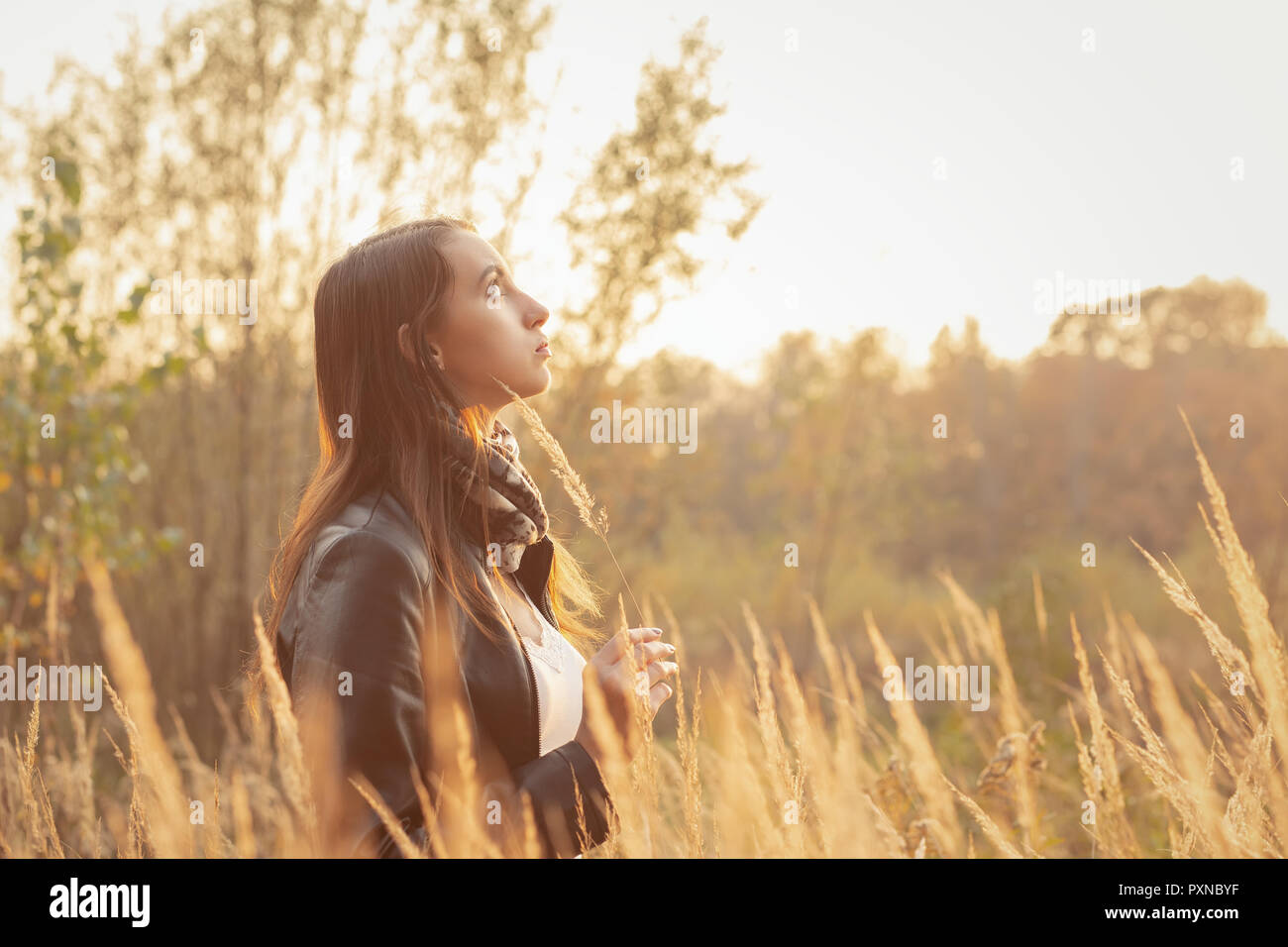Belle jeune femme triste marche à l'herbe sèche, vue de profil Banque D'Images