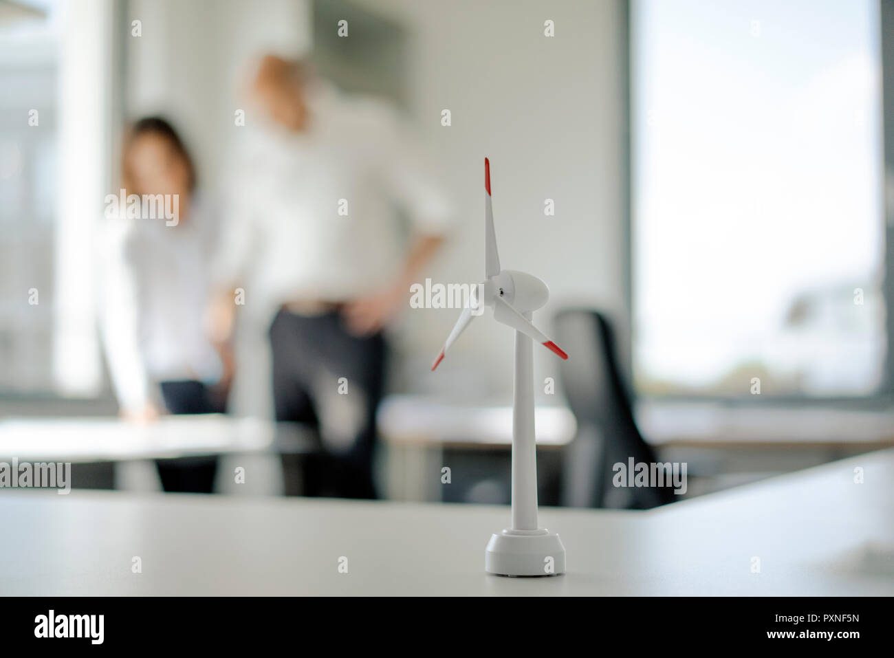 Modèle de roue éolienne sur étagère de bureau, avec deux personnes parlant en arrière-plan Banque D'Images