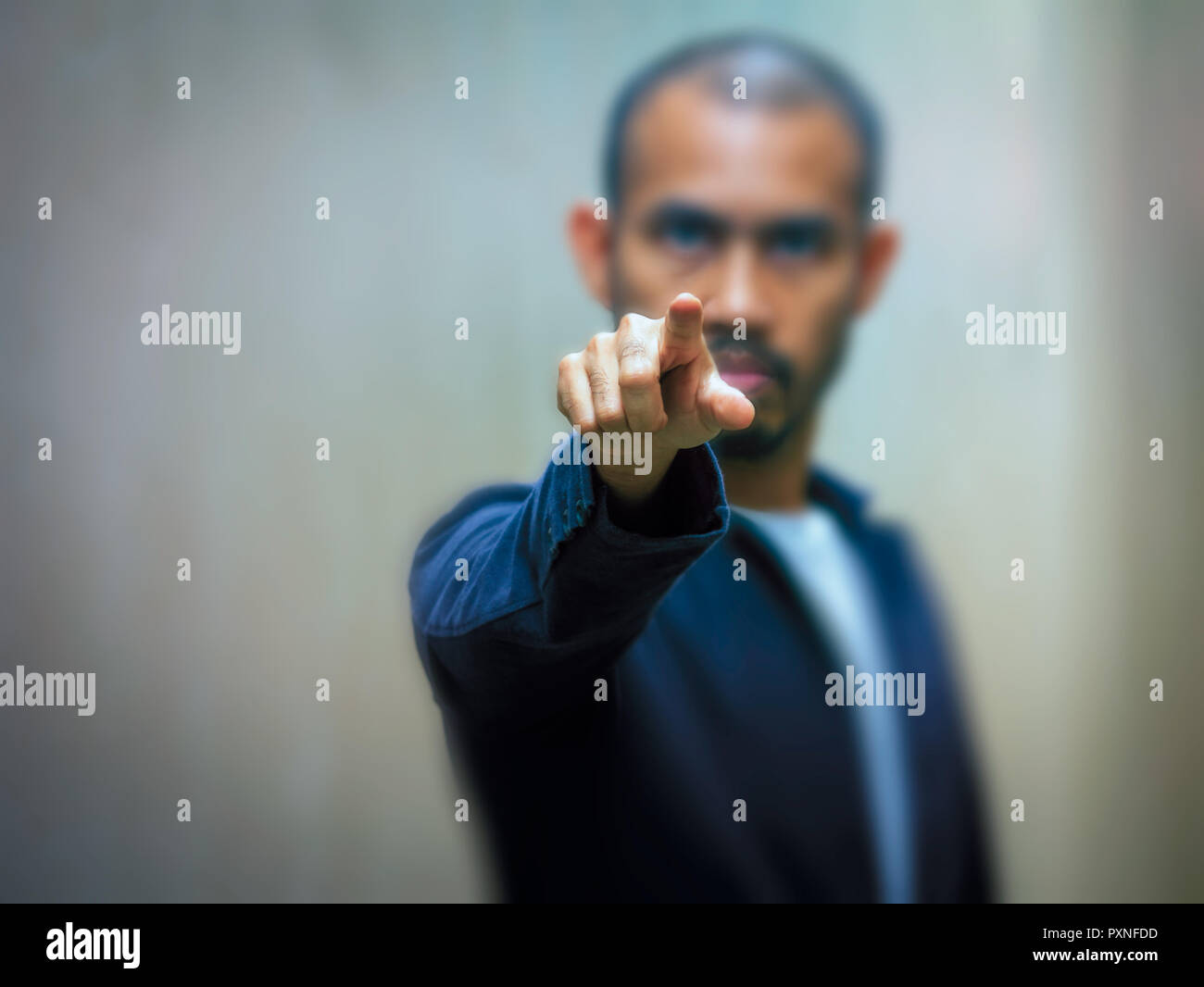 Un homme asiatique portant un maillot bleu points son doigt de l'avant avec une expression de colère.focus sélectif. Banque D'Images