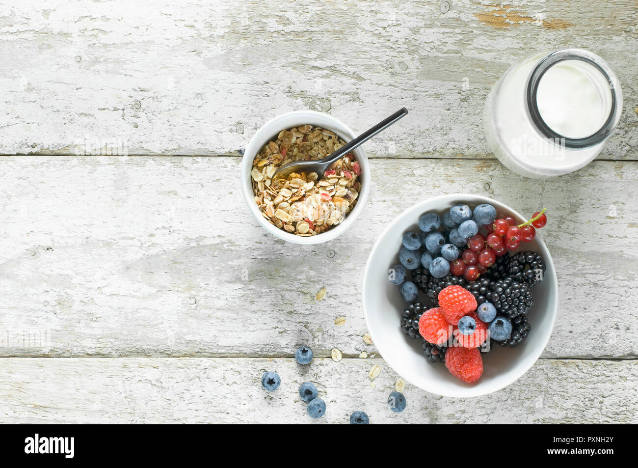 Bol de granola, bouteille de lait et un bol de fruits sur bois Banque D'Images