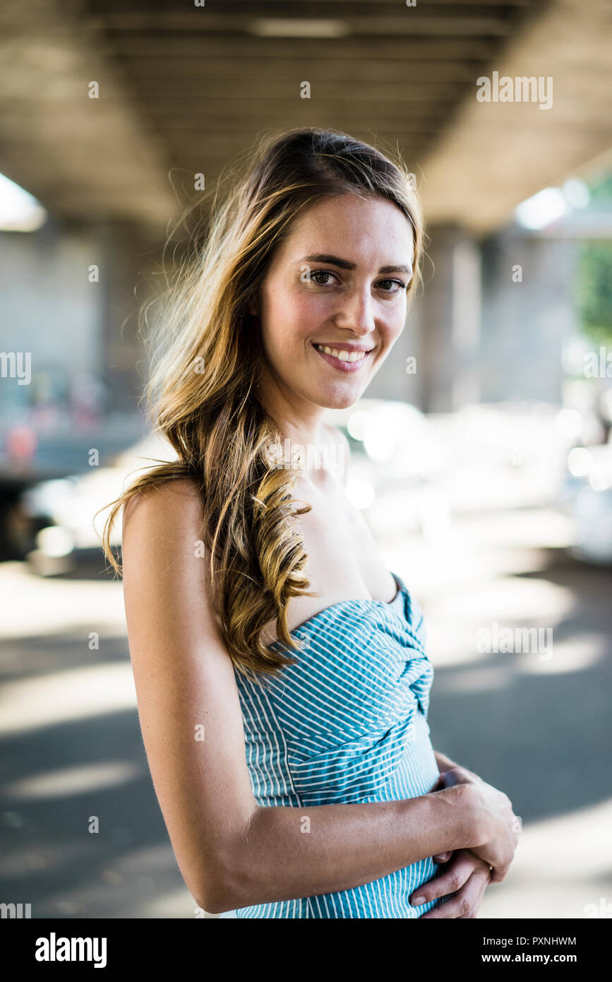 Portrait of smiling long-haired woman standing at passage sous Banque D'Images