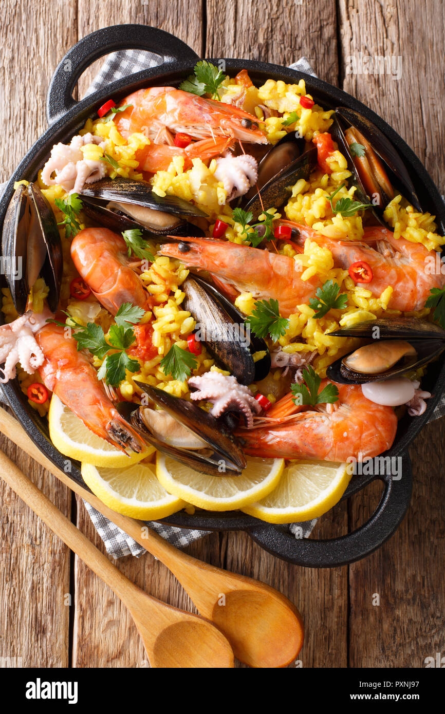 La Paella De Fruits De Mer Avec Crevettes Moules Poissons Et Le Bebe Poulpe Servi Dans Une Poele Sur Une Table En Bois Haut Vertical Vue De Dessus Photo Stock Alamy