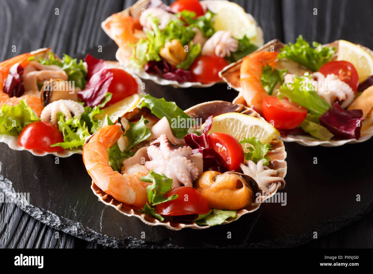 Salade De Fruits De Mer Gastronomique De Crevettes Poulpe Bebe Moules Calmars Et De Petoncles En Coquilles De Mer Gros Plan Sur La Table Verticale Photo Stock Alamy