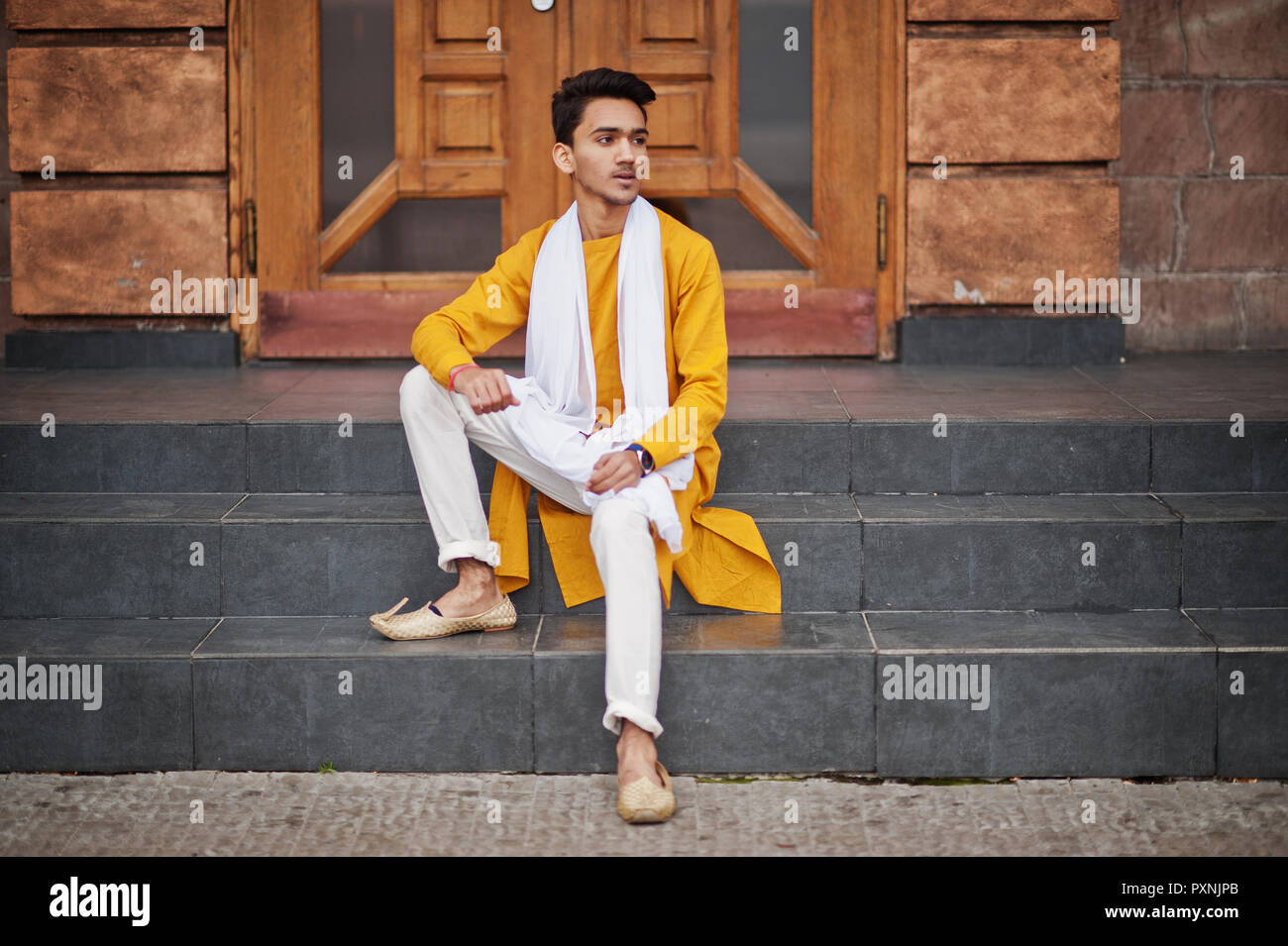 L'homme élégant indiennes en jaune vêtements traditionnels avec l'écharpe  blanche posée à l'extérieur Photo Stock - Alamy