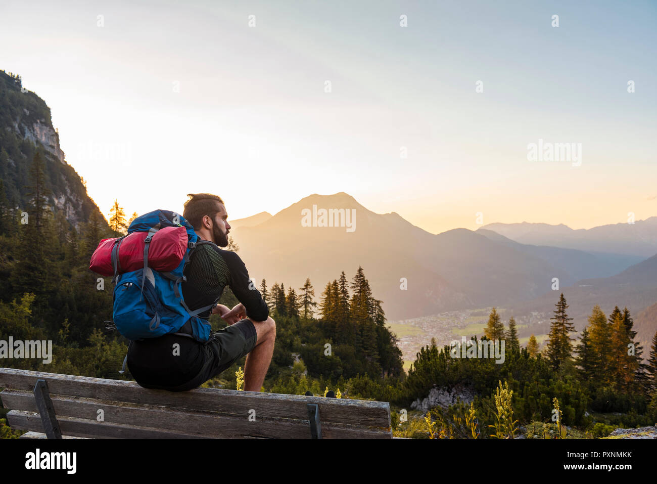 Autriche, Tyrol, randonneur prenant une pause, assis sur un banc, à la vue de Banque D'Images