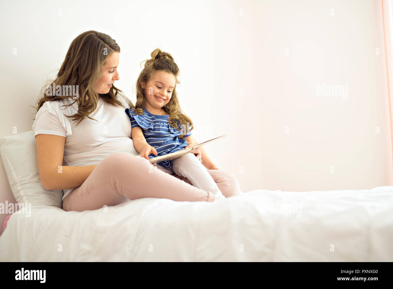 Portrait d'une mère et sa fille lire un livre de mensonge et de vous détendre dans le lit Banque D'Images